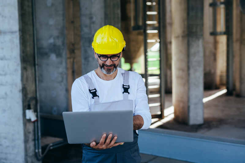 construction worker in yellow helmet using laptop