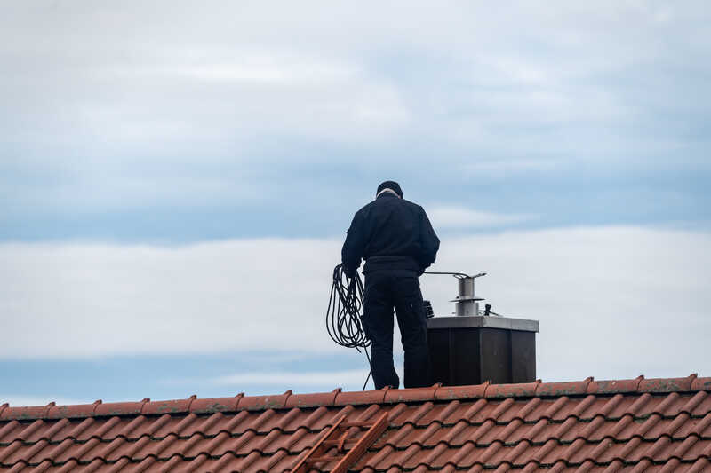 Chimney sweeper on the roof of a house