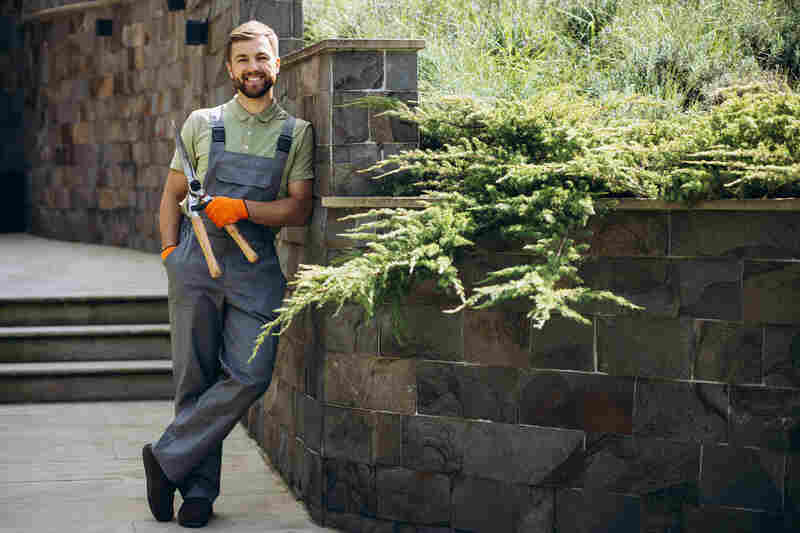 Professional landscaper holding scissors in the yard smiling